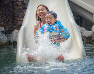 Asian boy and he mother play on the  slider water
