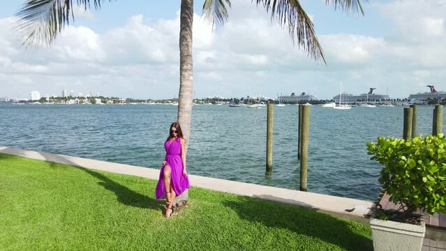 Lonely Sexy Woman With Long Legs in Pink Dress Standing by Palm Tree and Sea