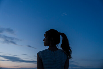 夕暮れの飛行場を眺める女性