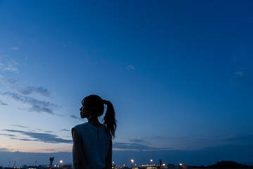 夕暮れの飛行場を眺める女性