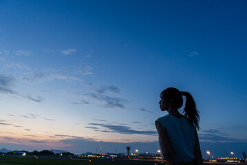 夕暮れの飛行場を眺める女性