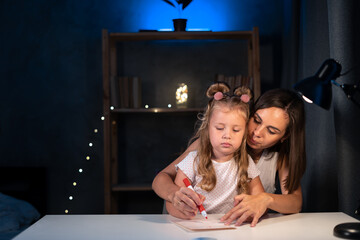 Mother teaches little preschooler to do homework by painting with color at night, image can be used...