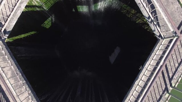 Arial zoom out shot from head down position. Dam hole in the middle of the lake. Bridge leading up to it. Lithuania.