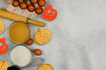 ingredients for homemade halloween cookies, farm eggs in eco-friendly cardboard packaging, rolling pin, whisk, flour and brown cane sugar.