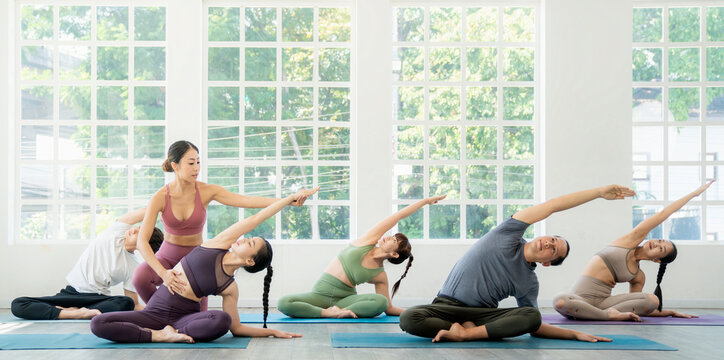 Asian yoga trainer and her student pose yoga basic position in her class room
