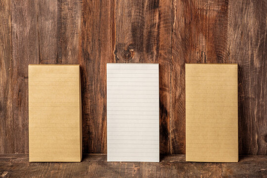 three of notepad lean at wood wall on wood table