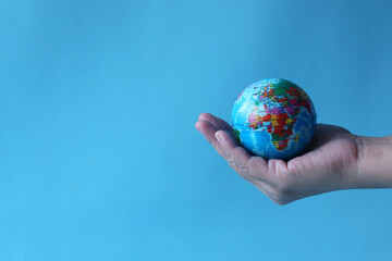 Earth globe in human hands on blue background for World Earth Day.