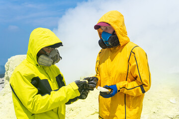 volcanologists on the slope of the volcano examines samples of minerals against the backdrop of...