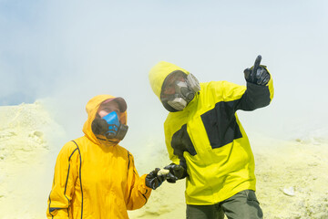 volcano scientists on the slope of the volcano collect samples of minerals against the backdrop of smoking sulfur fumaroles