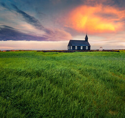 Obraz premium Nice sunrise in Iceland. Black wooden Budakirkja church. Fresh green summer view of Snafellsnes peninsula, western Iceland, Europe. Beauty of nature concept background..