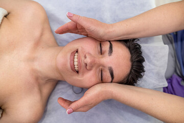 Fototapeta na wymiar young pretty woman receiving facial lifting massage at spa clinic
