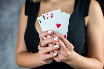 Brunette model bare shoulders in a black dress and holding cards on the background of cleavage