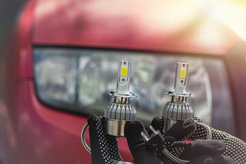 Car service where men hold a halogen lamp to repair or change a headlight.