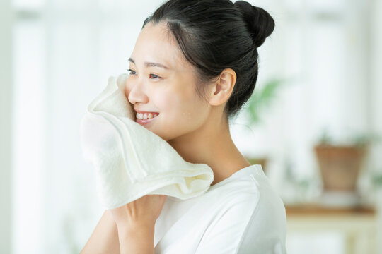タオルで顔を拭く若い女性