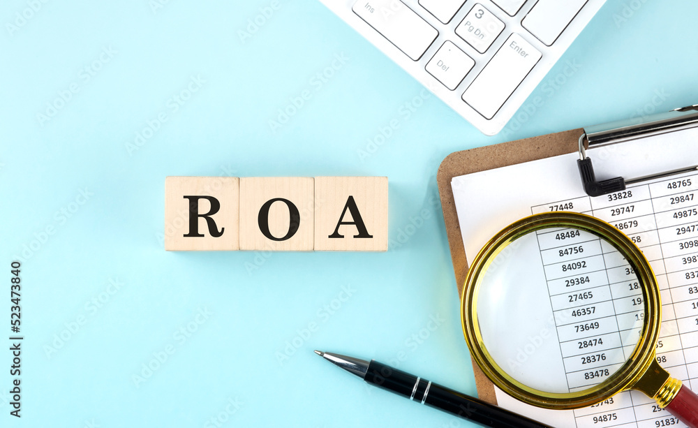 Aufkleber roa - return on assets word on a wooden cubes on blue background with chart and keyboard