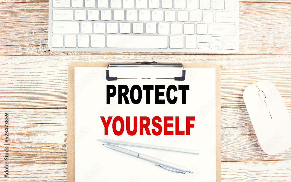 Aufkleber protect yourself text on a clipboard with keyboard on wooden background