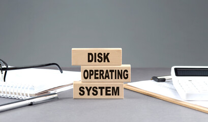 Disk Operating System text on wooden block with notebook,chart and calculator, grey background