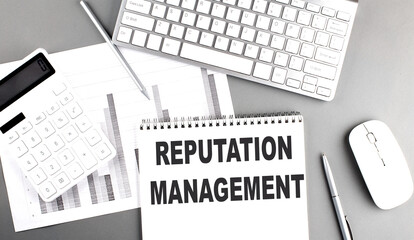 REPUTATION MANAGEMENT text written on notebook on grey background with chart and keyboard , business concept