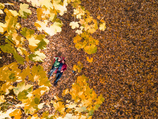 overhead view of woman with man laying down on the ground covered with autumn leaves © phpetrunina14