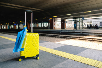 yellow valise with ukrainian flag at railway station