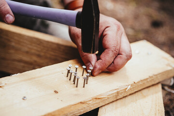 Male hands hammer a heart of nails into a board.