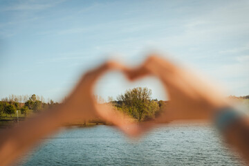 Tree seen from woman making heart shape