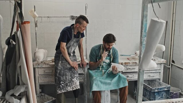 Two young adult Caucasian craftsmen sharing ideas on how to make prosthetic limbs more comfortable for their clients