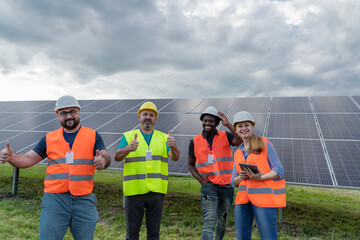 Happy engineers showing thumbs up gesture standing at solar power station