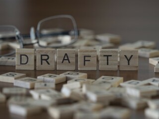 Drafty word or concept represented by wooden letter tiles on a wooden table with glasses and a book