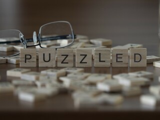 Puzzled word or concept represented by wooden letter tiles on a wooden table with glasses and a book