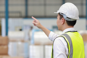 Rear view architect or engineering man and worker standing and pointing something while checking large warehouse. Asian business manager looking in future with warehouse building background.