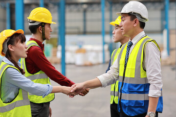 Group of technician engineer in protective uniform with hardhat standing and shaking hands celebrate successful together or completed deal commitment at industry warehouse manufacturing factory