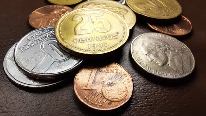 25 Peso cents and 1 Euro cent coins with a collection of various old coins on a brown background.