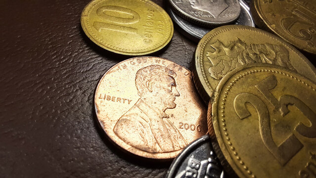 Dollar penny coin, with Abraham Lincoln’s image, together with a collection of various old coins on a brown background.