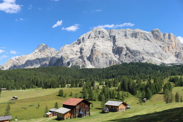 Fototapeta na wymiar Val Badia, Italy-July 17, 2022: The italian Dolomites behind the small village of Corvara in summer days with beaitiful blue sky in the background. Green nature in the middle of the rocks.