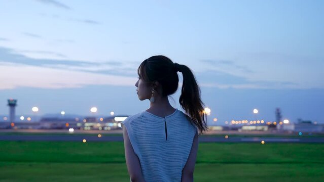 夕暮れの飛行場を眺める女性