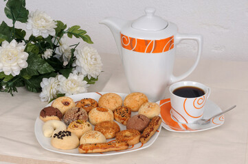 There is a pot of tea and homemade sweet cookies on the dining table.