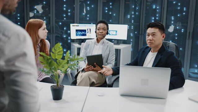 Group of people on business meeting in data center. Multi-ethnic experienced staff of IT workers communicating about business plans. Teamwork.