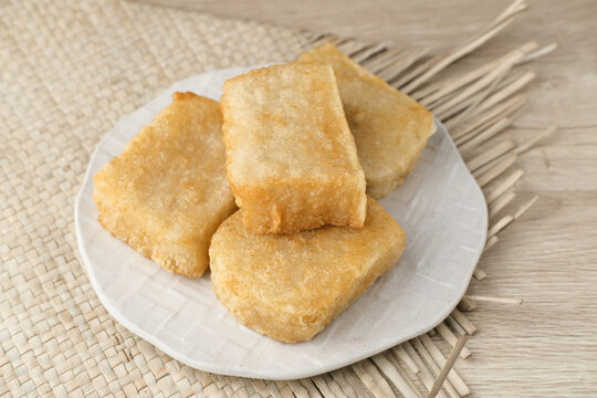 Jadah Goreng or Fried sticky rice cake is Javanese traditional cake made from glutinous rice and grated coconut. Served in white plate, selective focus image.
