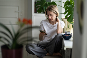 Serious middle-aged woman searches job on Internet special websites using smartphone. Hopeful...