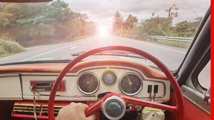 Driving and holding the steering wheel of an old car with the dashboard in view