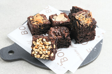 Homemade chocolate fudge brownie with mix topping, close up, served on plate, isolated on white background. Selective focus image.
