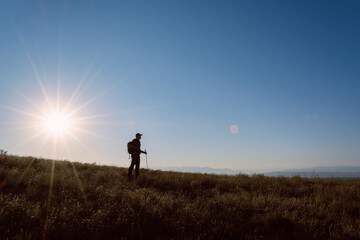 The traveler on the background of the sun. Rising sun. Leto. Kazakhstan.