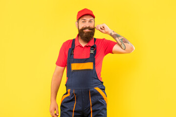 happy bearded man mechanic in work clothes on yellow background