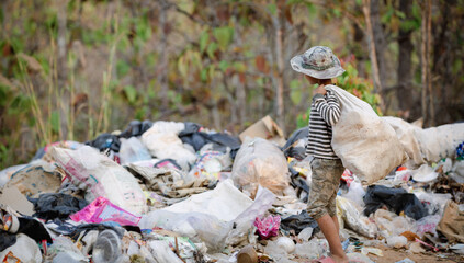 A poor Indian rag picker boy carrying a huge load of garbage collected during the day. Child labor...