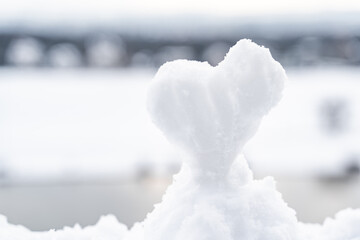 Heart shaped figure made of clear white snow on high hill on blurry background of Elbe river,...