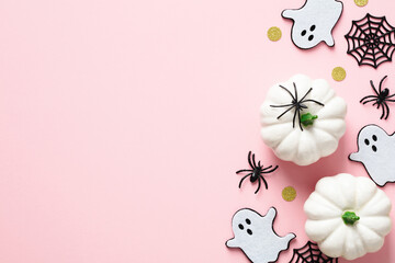 Cute Halloween decorations on pastel pink background. Flat lay ghosts, spiders, webs, white...