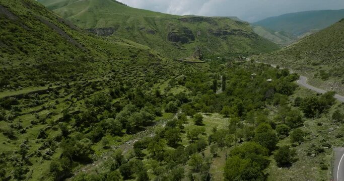 Towering Forested Mountains With Flowing River And Asphalt Road Overlooking Khertvisi Fortress In Southern Georgia. Aerial Wide Shot