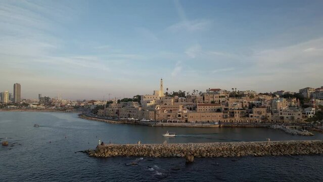 Aerial parallax of the old port of Jaffa above the sea as a boat leaves the port towards the open sea