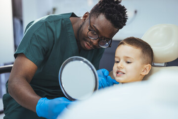 Cute little boy getting teeth exam at dental clinic. Child visit dentist. Cute boy in dental...